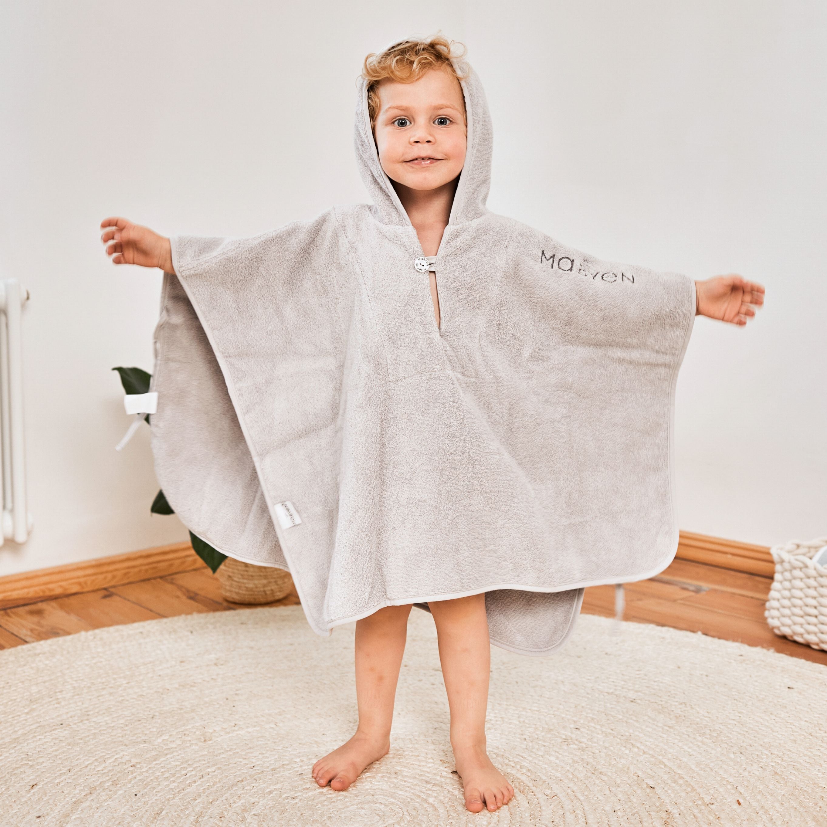 Kind in hellgrauen Poncho