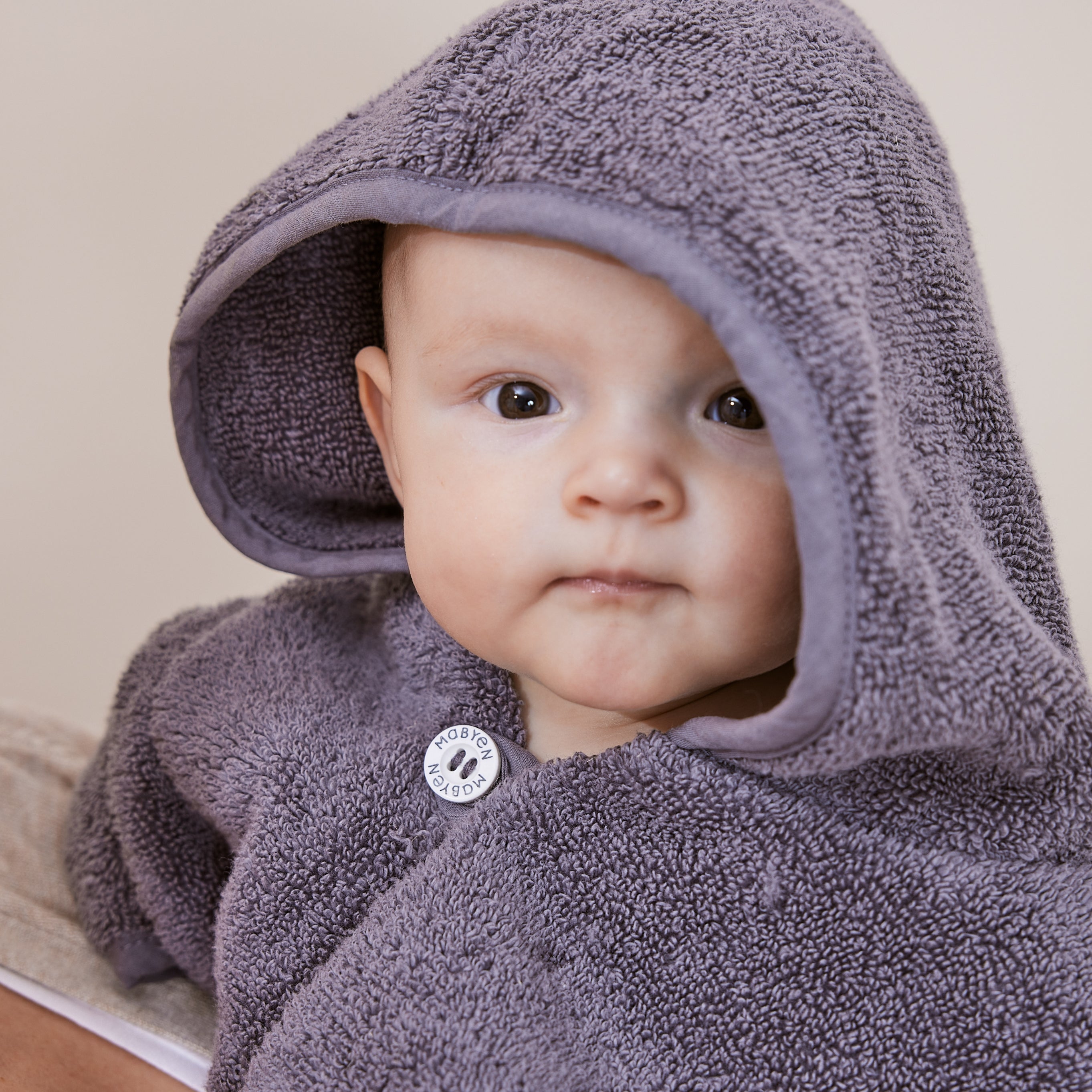 Kleines Baby mit dunkelgrauen Poncho
