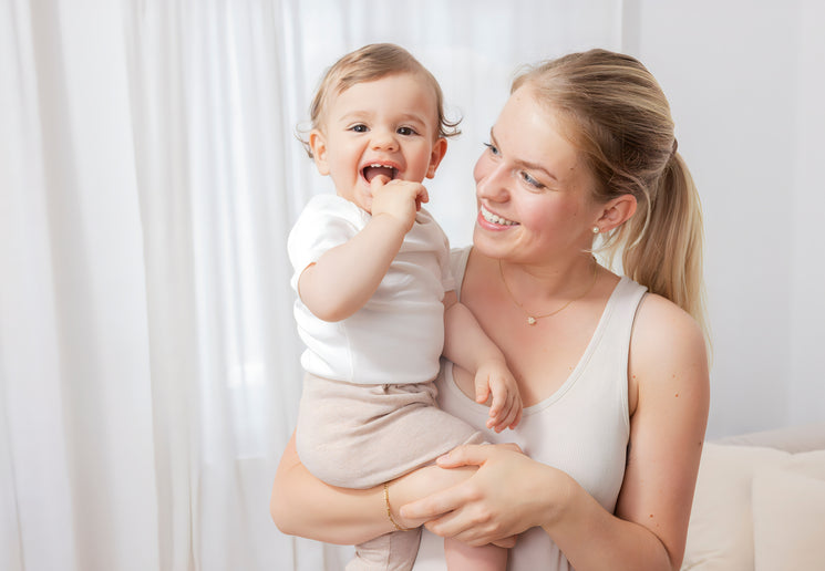 Mama hält Baby auf dem Arm beide lachen